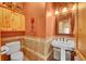 Powder room with wall-mounted sink, decorative mirror and sconce lighting, and half-tiled wall at 2433 Dogie Spur, Golden, CO 80403