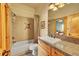 Bright bathroom featuring granite countertops, wood cabinets, and a shower-tub combo with tile surround at 2433 Dogie Spur, Golden, CO 80403