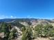 Beautiful mountain and valley view with abundant evergreens and charming home nestled in nature at 2433 Dogie Spur, Golden, CO 80403
