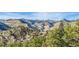 Expansive mountain range with snow capped peaks and lush green valleys beneath a vibrant blue sky at 2433 Dogie Spur, Golden, CO 80403
