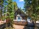 Charming cabin exterior with blue doors, a spacious deck, and surrounded by tall, mature trees at 91 Slalom Dr, Breckenridge, CO 80424