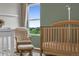 Comfortable Bedroom with a wooden crib, chair, and outside views from the window, creating a serene environment at 7218 Animas Ave, Frederick, CO 80530