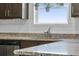 Close-up view of kitchen featuring stainless steel sink, granite countertops and white subway tile at 7218 Animas Ave, Frederick, CO 80530
