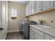 Bright laundry room boasts gray front-load washer, white cabinetry, and stylish wood-look tile flooring at 6878 Northstar Ct, Castle Rock, CO 80108