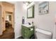 Cozy bathroom featuring a green vanity, white walls, and a view to the hall and bedroom at 1519 S Lowell Blvd, Denver, CO 80219