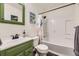 Well-lit bathroom featuring a shower-tub combo and green vanity with ample storage at 1519 S Lowell Blvd, Denver, CO 80219