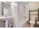 Bright bathroom featuring a pedestal sink, white tiled shower-tub, and convenient toilet with storage rack at 8100 W Quincy Ave # D, Littleton, CO 80123