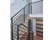 Staircase with a black metal railing, light wood stairs, and a view of the open lower level at 1819 N Grove St, Denver, CO 80204