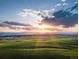 Scenic landscape view showcasing the sun rising over a vibrant green field, evoking peace and tranquility at 39733 Penn Rd, Elizabeth, CO 80107