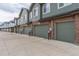 Row of attached garages with neutral colored doors and brick detailing on townhouses at 5187 S Fairplay St, Aurora, CO 80015