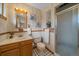 Traditional bathroom with a wood vanity, tiled shower, and floral wallpaper accents at 6940 S Uinta St, Centennial, CO 80112