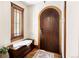 Welcoming entryway with a dark wood arched door, and a wooden bench at 2591 Albion St, Denver, CO 80207
