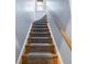 Carpeted staircase with wooden handrail ascends to the next level, illuminated by a window at the top of the stairs at 2591 Albion St, Denver, CO 80207