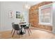 Charming dining room showcases an exposed brick wall, natural light, and an elegant round table for intimate gatherings at 480 S Grant St, Denver, CO 80209