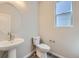 Well-lit half bathroom with a pedestal sink, modern fixtures, and a stylish round mirror at 2702 E 103Rd Ave, Thornton, CO 80229