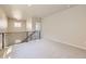 Bright bonus room featuring neutral walls, plush carpet, and modern black metal railings at 2702 E 103Rd Ave, Thornton, CO 80229