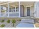 View of the front porch with columns, white railings, and stone landscaping leading to a gray door at 2702 E 103Rd Ave, Thornton, CO 80229