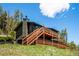 An inviting exterior view showcasing a multi-level deck and a wood-sided home against a bright blue sky at 34075 Grouse Ln, Evergreen, CO 80439