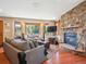 Living room featuring a stone fireplace, wood floors, bay window overlooking the treeline, and cozy seating at 34075 Grouse Ln, Evergreen, CO 80439