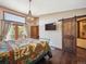 Cozy main bedroom with warm lighting, hardwood floors, stylish chandelier, and access to a private balcony at 34075 Grouse Ln, Evergreen, CO 80439