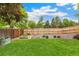 Backyard featuring a wooden fence, lush grass, gravel area, and raised garden beds at 13701 Yank Way, Arvada, CO 80004