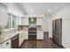 Bright kitchen features white cabinets, stainless appliances, and a farm style sink at 13701 Yank Way, Arvada, CO 80004