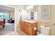 Bathroom featuring double sinks, wood cabinets, and walk-in access to bedroom at 3595 E 124Th Pl, Thornton, CO 80241