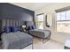 Bright bedroom with two twin beds, a navy accent wall, and large windows at 6770 Zebra Grass Ln, Parker, CO 80138