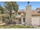 Exterior view of a home with a stone chimney, fenced in area, and mature trees at 15912 E Dakota Pl # C, Aurora, CO 80017