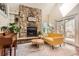 Living room featuring a stone fireplace, plants, yellow couch, neutral area rug and hardwood floors at 15912 E Dakota Pl # C, Aurora, CO 80017
