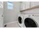Well-lit laundry room featuring a modern washer and dryer set and ample cabinet space for storage at 5988 N Boston St, Denver, CO 80238