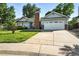 Landscaped front yard highlights this inviting residence, boasting a two-car garage and blue front door at 5193 S Flanders Ln, Centennial, CO 80015