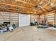 Spacious garage interior featuring a large door, concrete floor, and exposed wooden beam ceiling at 47855 E 88Th Ave, Bennett, CO 80102