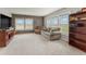 Bright living room featuring a stone accent wall, plush carpet, and large windows offering plenty of natural light at 47855 E 88Th Ave, Bennett, CO 80102