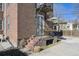 Brick porch with wrought iron railing and seasonal potted plants leading to front door at 2034 Dahlia St # 1, Denver, CO 80207