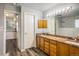 Modern bathroom with double sink vanity, warm wood cabinets, and a view into the walk in shower at 2777 W 106Th Cir, Denver, CO 80234