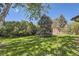 The sprawling backyard features lush lawn, mature trees, and a red storage shed at 3825 S Peach Way, Denver, CO 80237
