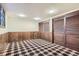 Finished basement features knotty pine wainscoting, a plaid carpet, two windows and two storage closets at 3825 S Peach Way, Denver, CO 80237
