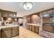 Spacious kitchen with brick accent wall, wood cabinets, and hardwood floors flowing into sitting room at 3825 S Peach Way, Denver, CO 80237