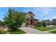 Attractive two-story home with a well-maintained lawn, mature tree, and brick-accented entryway at 19382 Dunraven St, Parker, CO 80134