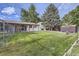 Large, fenced backyard featuring green grass, mature trees, a storage shed and patio at 11310 W 46Th Ave, Wheat Ridge, CO 80033