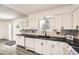 Updated kitchen with black countertops, white cabinets, open shelving, and stainless dishwasher at 11310 W 46Th Ave, Wheat Ridge, CO 80033