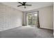 Bright bedroom with gray carpet, exposed brick wall, ceiling fan, and sliding glass doors to outdoor balcony at 9605 E Kansas Cir # 53, Denver, CO 80247