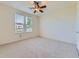 Sunlit bedroom with neutral carpet, ceiling fan, and a window overlooking the outdoors at 448 Bonanza Dr, Erie, CO 80516