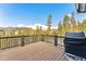 Wooden deck with black railings overlooking trees and mountains, featuring a grill at 1279 Estates Dr, Breckenridge, CO 80424