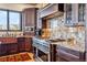 Close up view of stainless steel stove and hood with granite backsplash and custom cabinets at 1279 Estates Dr, Breckenridge, CO 80424