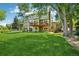 Spacious backyard showing a well-manicured lawn, mature trees, a wooden deck, and a partially shaded yard at 7999 Centrebridge Dr, Niwot, CO 80503