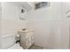 A bright bathroom featuring white tiled walls, a toilet, and a vanity at 6981 Zuni St, Denver, CO 80221