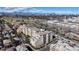 A panoramic aerial view of a multi-story condo complex with surrounding greenery, nearby shops, and a city skyline backdrop at 2500 E Cherry Creek South Dr # 213, Denver, CO 80209