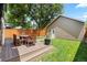 Backyard featuring a deck, wood fence, green lawn, and detached garage at 1366 S Vine St, Denver, CO 80210